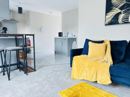 sala de estar con sofá azul y manta amarilla en Brand New 1 Bed Apartment, 5min Walk to Racing & Main Strip, with Electric Parking Bay & Terrace LONG STAY WORK CONTRACTOR LEISURE - CITRINE en Newmarket