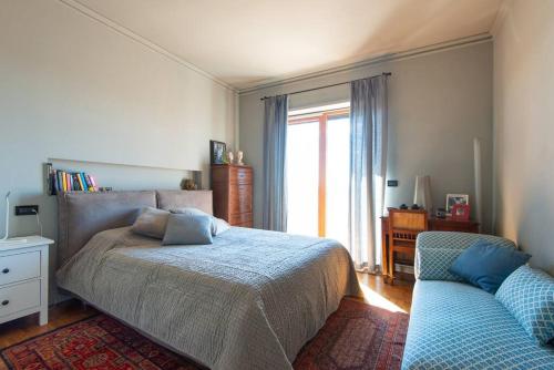 - une chambre avec un lit, un canapé et une fenêtre dans l'établissement Casa No.Na - Attico panoramico a Cherasco, à Cherasco