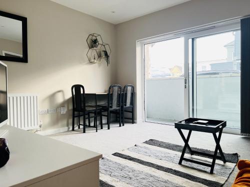 a living room with a table and a balcony at Brand New 1 Bed with Sofabed, Private Patio & Electric Parking Bay, 5min Walk to Racing & Main Strip LONG STAY WORK CONTRACTOR LEISURE - AMBER in Newmarket