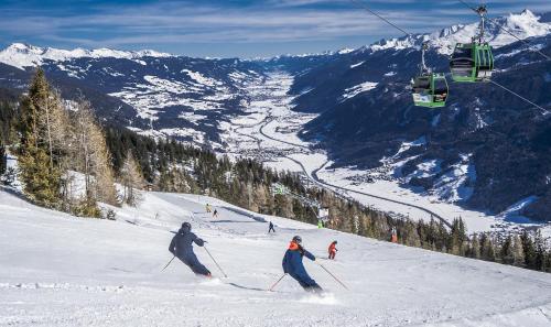 two people skiing down a snow covered slope with a ski lift at Am Waldrand 252 in Neukirchen am Großvenediger
