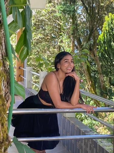 a woman in a black dress sitting on a railing at Bloomfield Farmhouse and Eco-Resort in Darjeeling