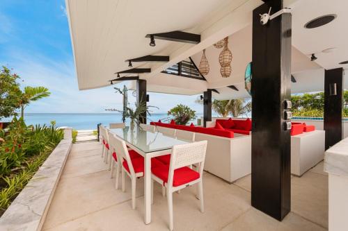 an outdoor dining room with a table and chairs and the ocean at Beachfront Villa Baan Paradise in Laem Set Beach