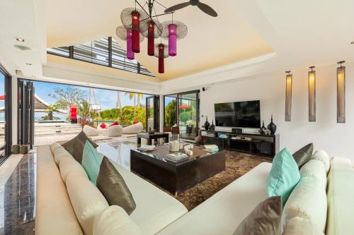 a living room with a couch and a tv at Beachfront Villa Baan Paradise in Laem Set Beach