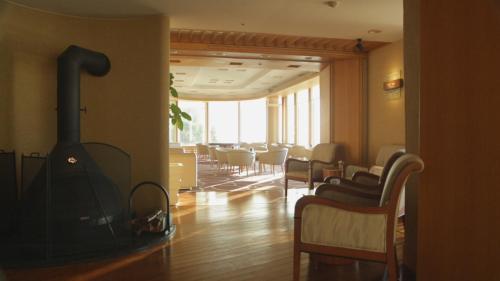 a living room with a stove in a room with chairs at 焼津グランドホテル in Hanazawa