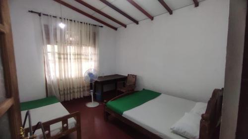 a room with two beds and a desk and a window at Happy Raydiant villa in Anuradhapura