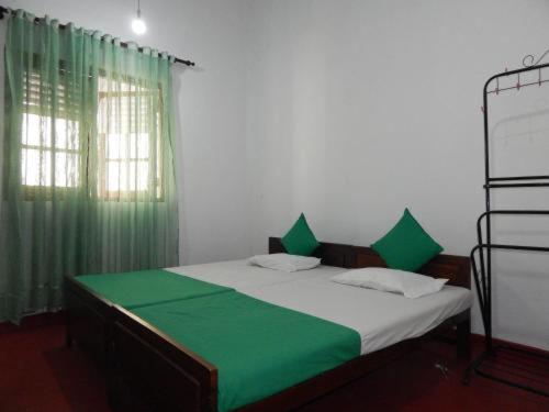 a bedroom with a bed with green sheets and a green curtain at Happy Raydiant villa in Anuradhapura