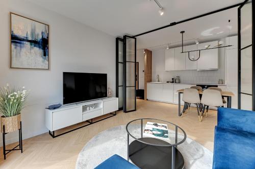 uma sala de estar com uma televisão e uma mesa em Downtown Apartments Angielska Grobla - City Center & Parking em Gdansk