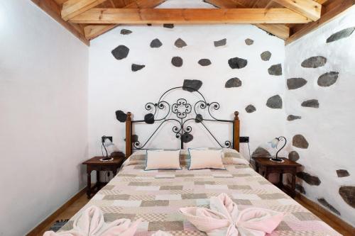 - une chambre avec un grand lit orné de fleurs roses sur le mur dans l'établissement Casa Rural Medina 2, à San Sebastián de la Gomera
