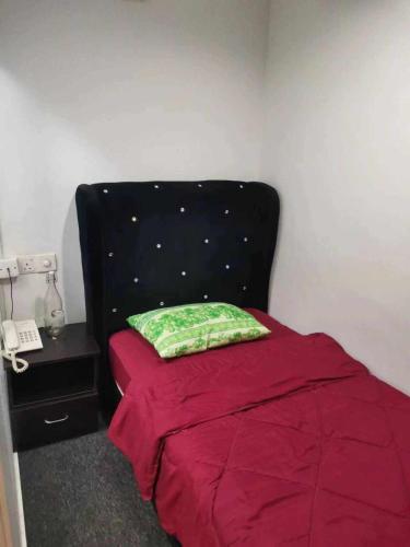 uma cama com uma cabeceira preta e uma almofada verde em Mikayla Hotel em Port Dickson