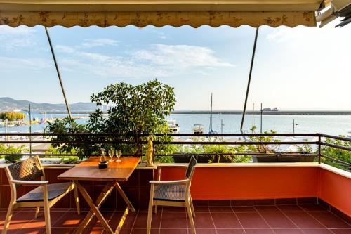 a table and chairs on a balcony with a view of the water at Grand Luxury Apartment Seafront Kalamata in Kalamata