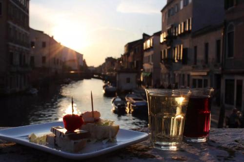 a plate of food and a drink on a table next to a canal at Ca'Rosa in Venice