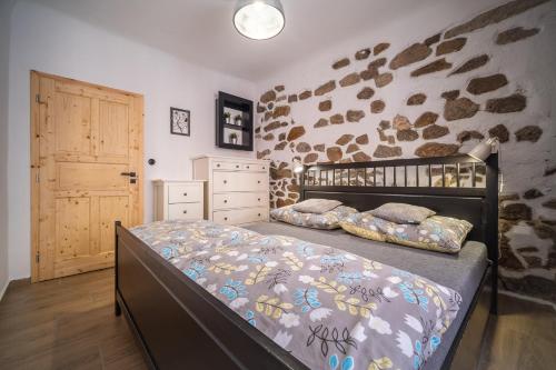 a bedroom with a bed and a stone wall at Apartmánový dům Jeník in Nové Hrady