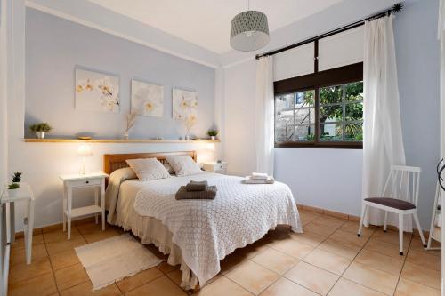 een witte slaapkamer met een bed en een raam bij La Huerta in Hermigua