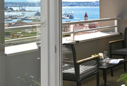 een kamer met een balkon met uitzicht op de oceaan bij Apartment TRI MASLINE in Trogir