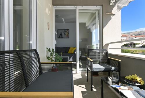 a balcony with chairs and a table and a living room at Apartment TRI MASLINE with seaview in Trogir
