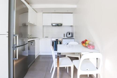 une cuisine blanche avec une table et des chaises blanches dans l'établissement Central and Parisian style - 3 bedrooms, à Paris