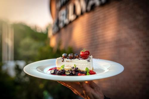a person holding a piece of cake on a plate at Hotel Bulwar in Toruń