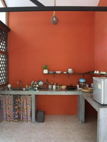 - une cuisine avec un évier et un mur rouge dans l'établissement Cocohut Garden, 