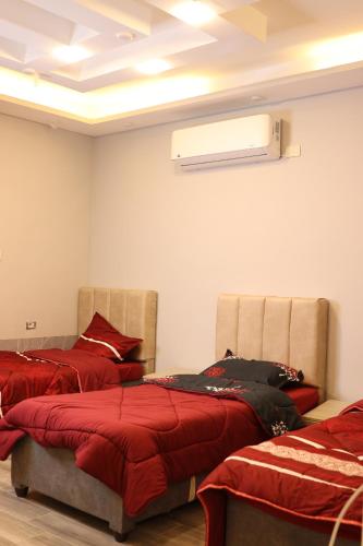 Habitación con 2 camas con sábanas rojas y techo. en شاليه ڤيو VIEW Chalet en Sowayma