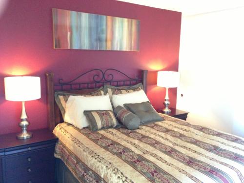 a bedroom with a bed with purple walls and two lamps at Desert Getaway in Desert Hot Springs