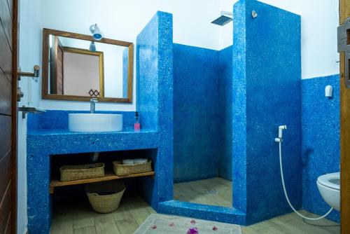 a blue bathroom with a sink and a mirror at Beachfront Villa Thamani with Private Pool and Beach ZanzibarHouses in Pwani Mchangani