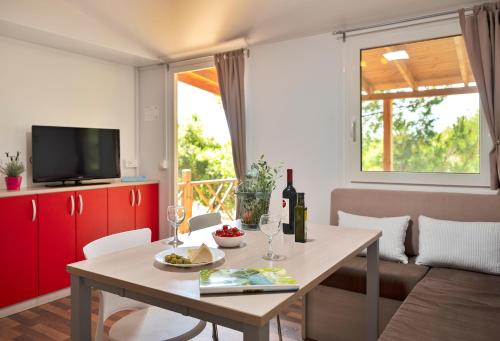 a living room with a table with a bottle of wine at Mobile Homes Camp Perna - Adriatic Kampovi in Orebić
