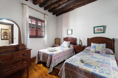 1 dormitorio con 2 camas, tocador y espejo en Casa de Telégrafos, en Vallehermoso