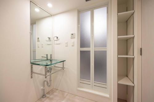 a bathroom with a glass sink and a mirror at Quador Waseda in Tokyo