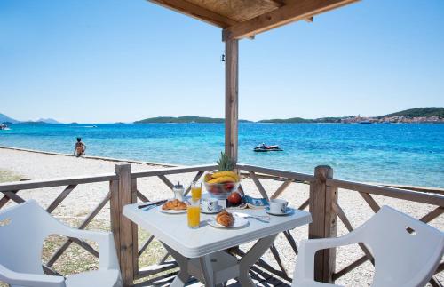 a table with a plate of food on the beach at Mobile Homes Camp Perna - Adriatic Kampovi in Orebić