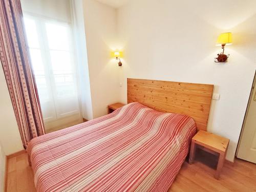 a small bedroom with a bed with a striped blanket at La Cardabelle, T2, centre Luchon, wifi, casier à ski, ascenseur, 4 personnes in Luchon