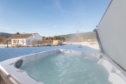 a jacuzzi tub in the middle of a snow covered yard at Chalet du Bien-être 15p. Piscine,Spa, Hammam,Pétanque,Basket in Gérardmer