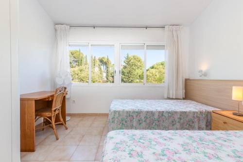 a bedroom with two beds and a desk and a window at Fantàstic s'agaró in S'Agaro