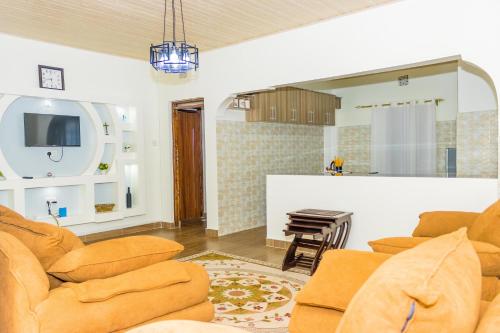a living room with orange chairs and a kitchen at Homely Escapes in Nanyuki