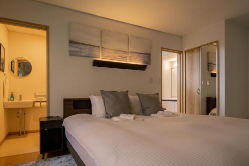 a bedroom with a large white bed and a mirror at Casi 15 in Furano