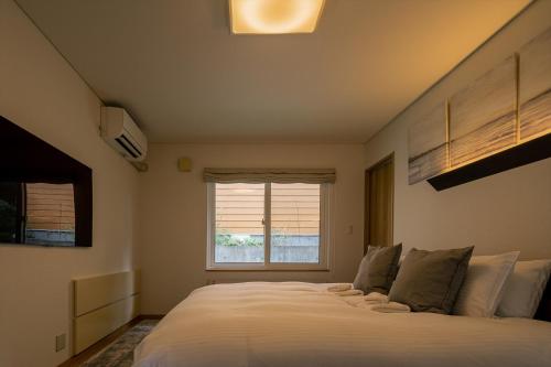 a bedroom with a large white bed with a window at Casi 15 in Furano