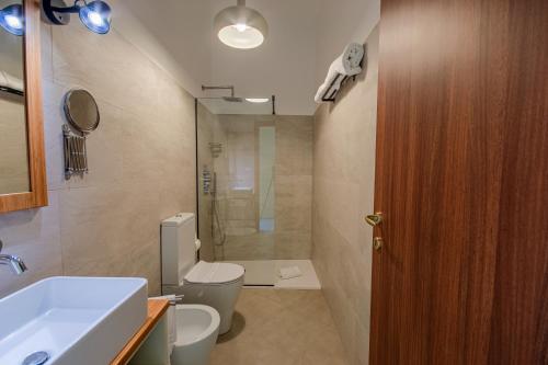 a bathroom with a toilet and a sink and a shower at La Scivola Rooms in Acitrezza
