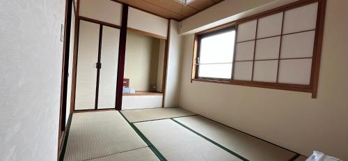 an empty room with a door and a window at World Business Hotel in Iida