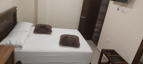 a white bed with two fuzzy pillows on it at APARTAHOTEL LION in Tuluá