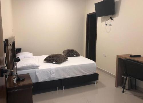 a bedroom with a bed with white sheets and pillows at APARTAHOTEL LION in Tuluá