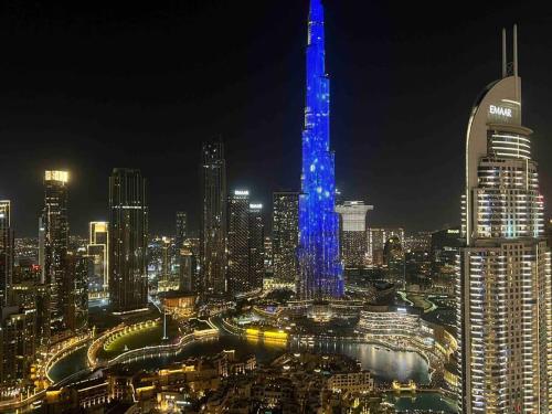 eine Skyline der Stadt in der Nacht mit einem blau beleuchteten Gebäude in der Unterkunft 3BR, Burj Khalifa,Fountain48 in Dubai