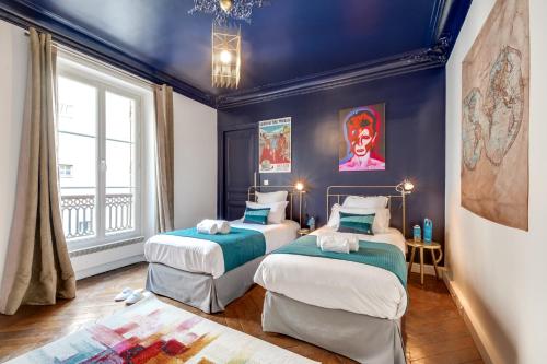 two beds in a room with blue walls at Sweet Inn - Rue de Rivoli in Paris