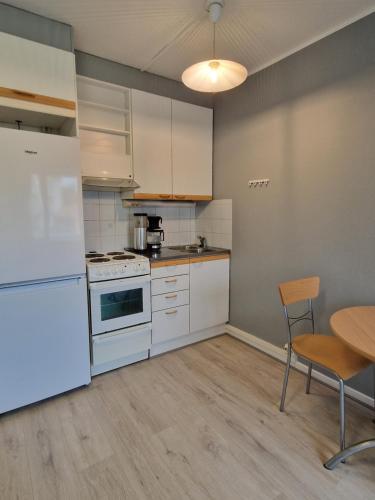 a kitchen with white appliances and a table and chairs at Humppilantie in Jokioinen