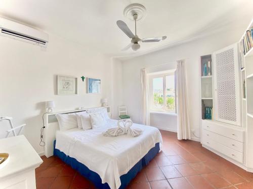 a white bedroom with a bed and a ceiling fan at Casa Romano, centro di Forio, Ischia in Ischia