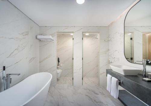 a bathroom with a tub and a sink and a mirror at JOUDYAN Red Sea Mall Jeddah By ELAF in Jeddah
