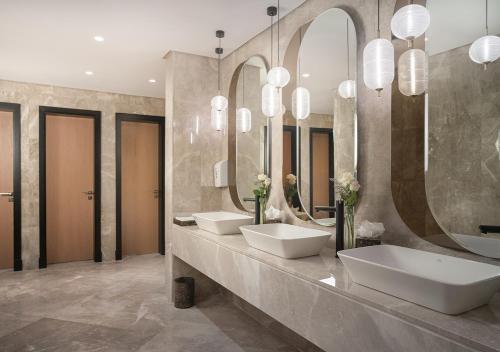 a bathroom with three sinks and two mirrors at JOUDYAN Red Sea Mall Jeddah By ELAF in Jeddah