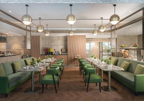 a restaurant with long tables and green chairs at JOUDYAN Red Sea Mall Jeddah By ELAF in Jeddah