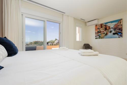 - une chambre blanche avec un grand lit et une grande fenêtre dans l'établissement Penthouse with sea views in Nueva Andalucia, à Marbella