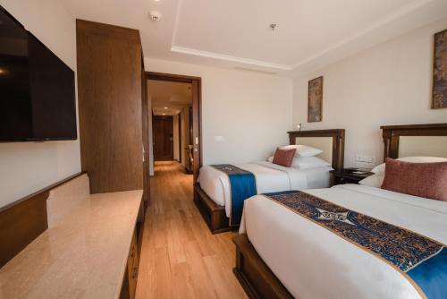 a hotel room with two beds and a flat screen tv at Ramayana Suites and Resort in Kuta