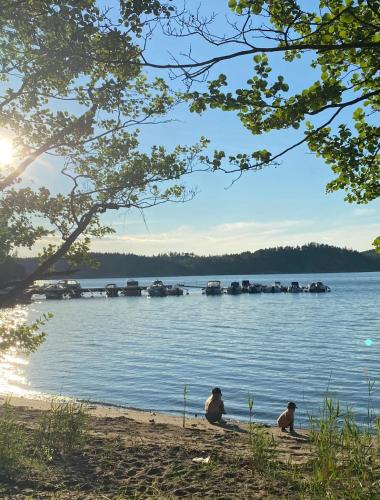 two people sitting on the shore of a lake with boats in the water at Apartment Ormestad in Uddevalla