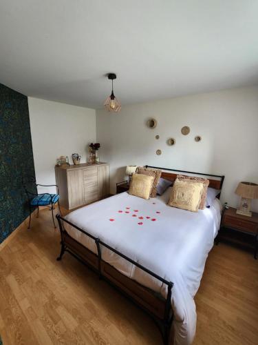 Un dormitorio con una gran cama blanca con flores rojas. en Chambre d'hôte la Coquierrerie, en Sottevast
